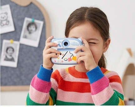 Girl taking photo with blue cat-shaped kids instant print camera